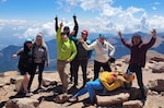 eight people pose for a fun photo with mountains in the background