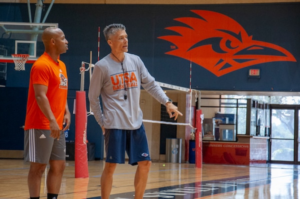 Darden and another member of coaching staff talk on sideline of basketball court