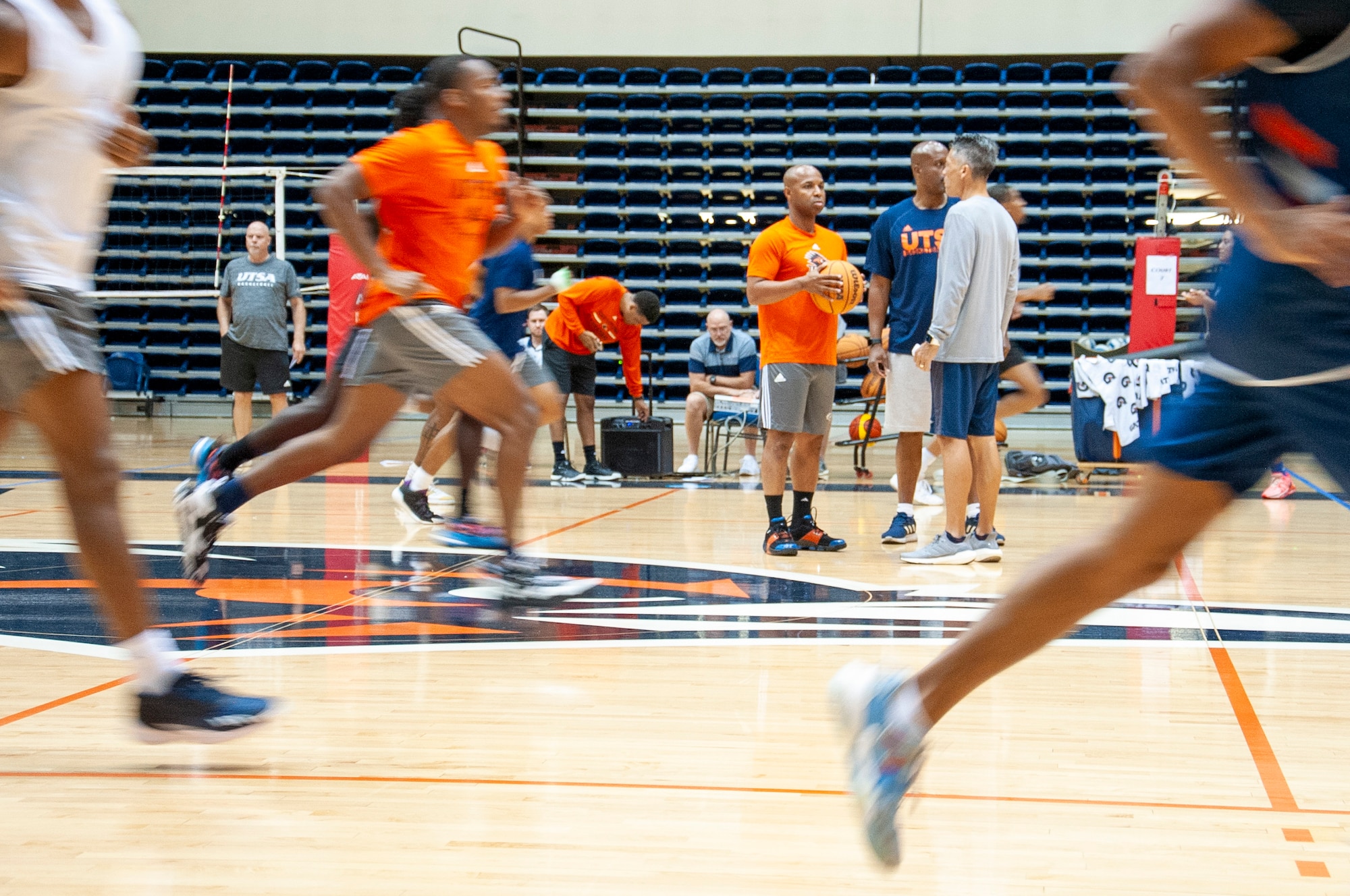 Darden talking with staff while players run in foreground.