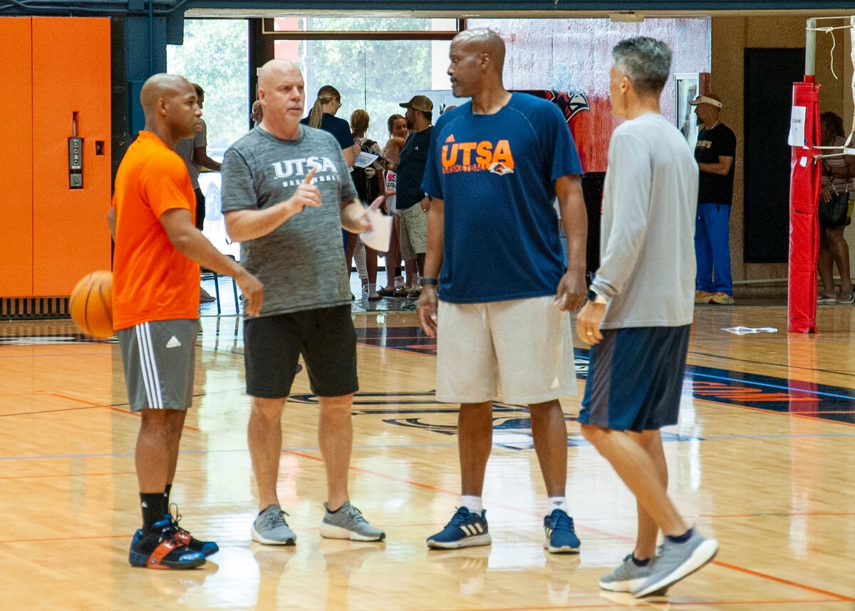 Darden and other coaches stand and talk on the court