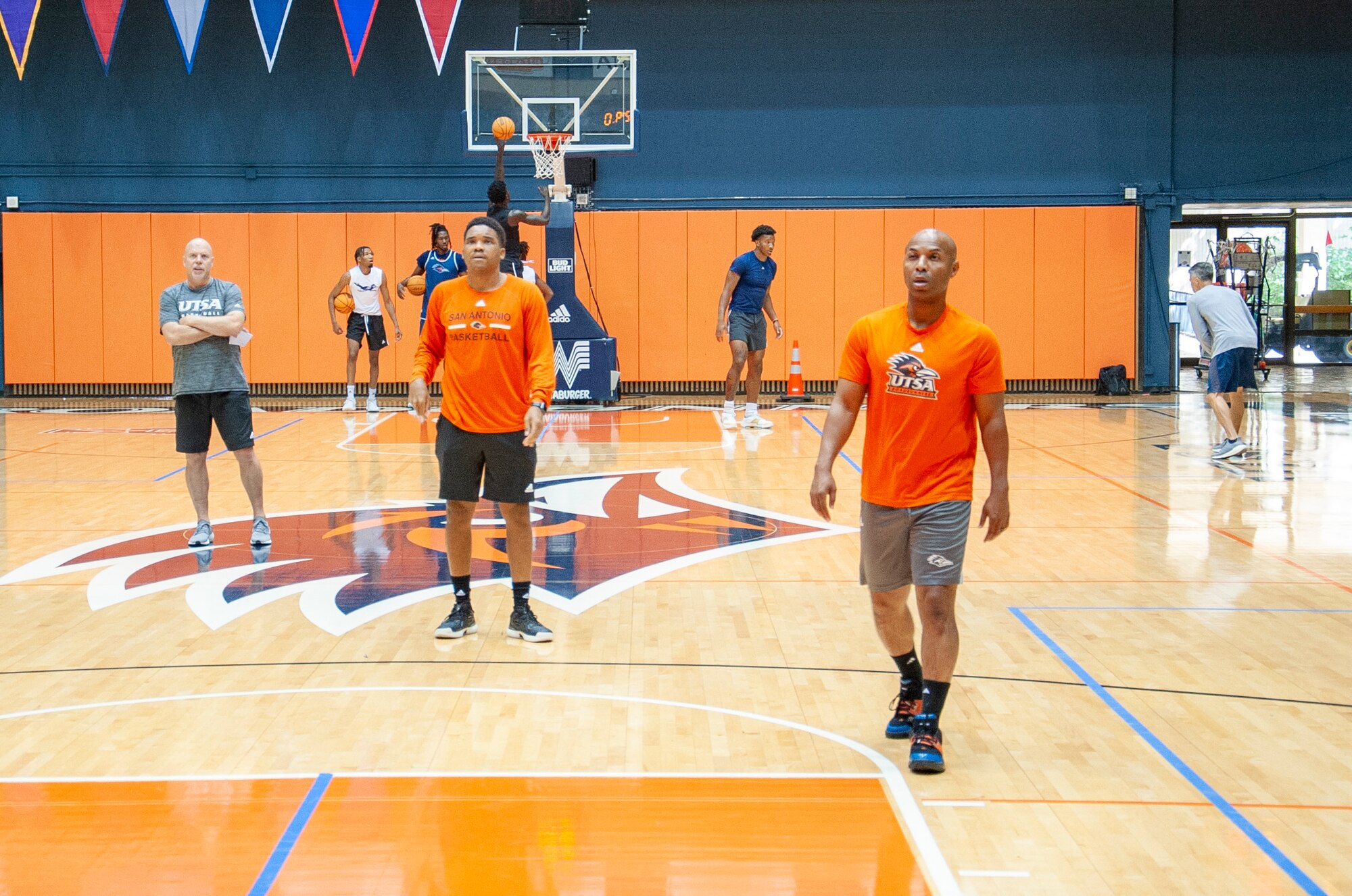Darden walking on a court with players running drills in the background
