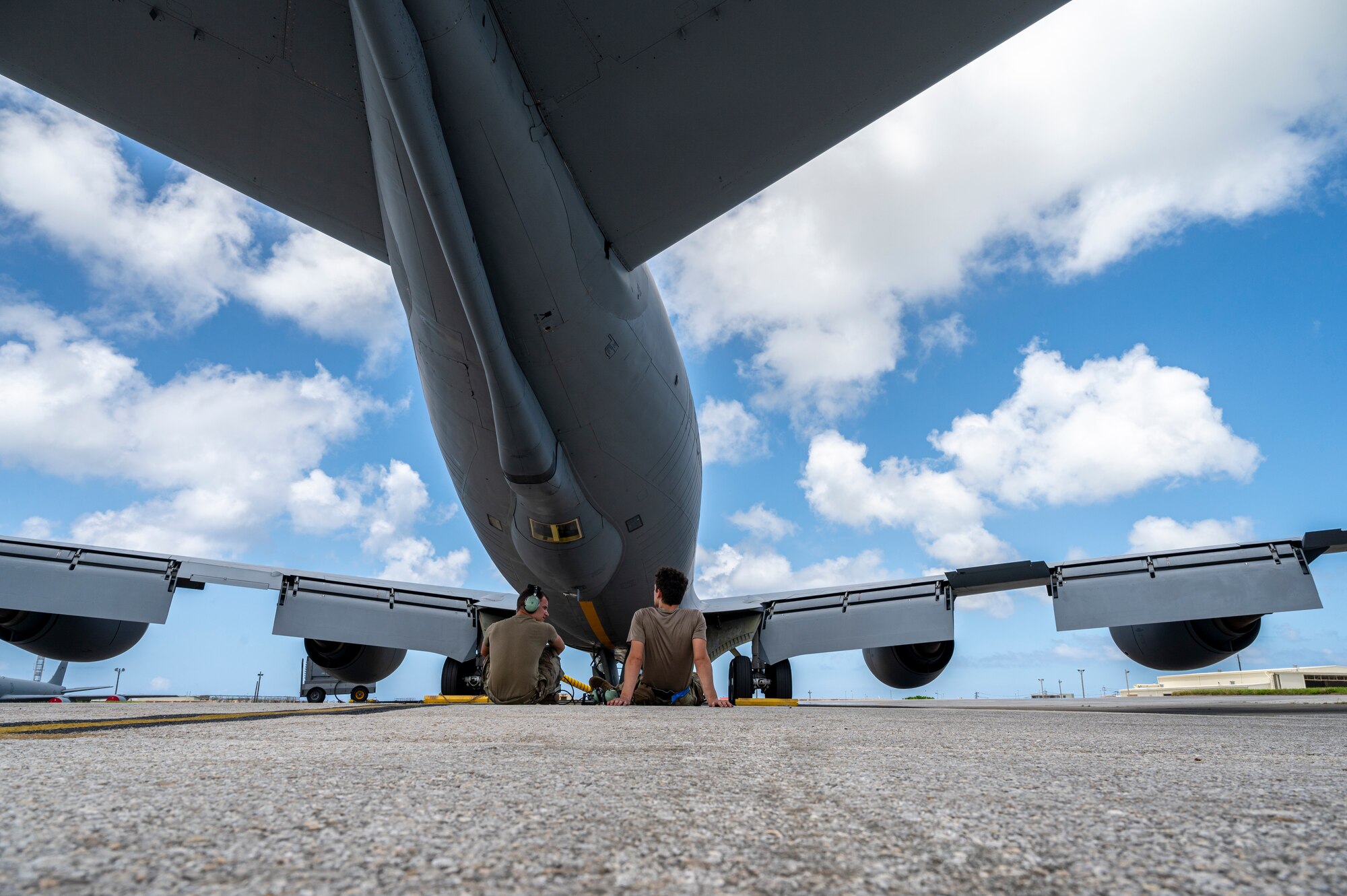 U.S. Air Force Senior Airmen Dominic Fontenot, 909th Air Refueling Squadron avionics journeyman and Colby Mall, 909th ARS aerospace propulsion journeyman, sit under a KC-135 Stratotanker before a refueling mission at Kadena Air Base, August 30, 2023.
