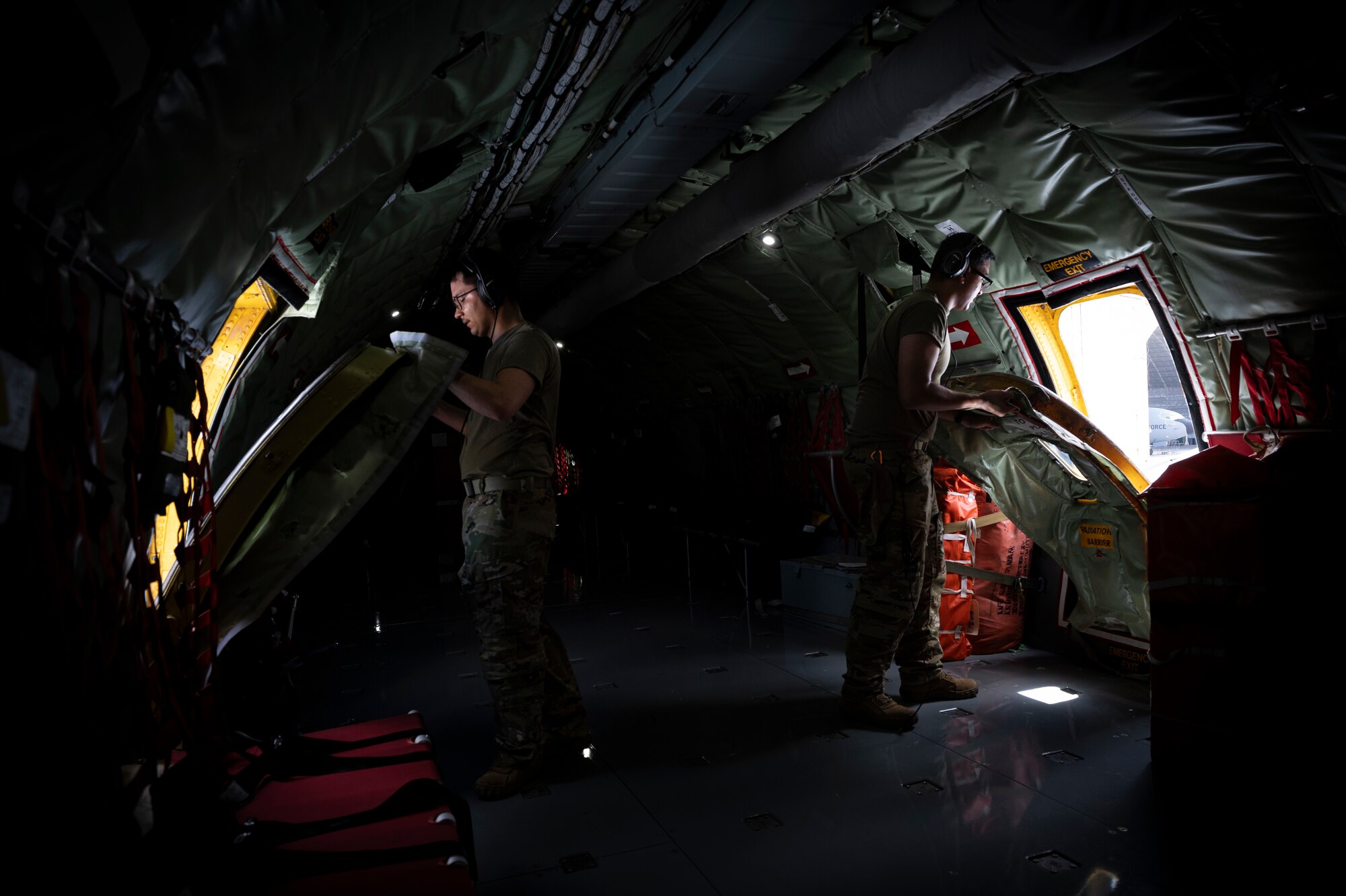 U.S. Air Force Senior Airman Christian Lawhorn and Airman First Class Brennan Rodriguez, 909th Air Refueling Squadron boom operators, secure overwing emergency exit hatches before a refueling mission at Kadena Air Base, Aug. 30, 2023. The