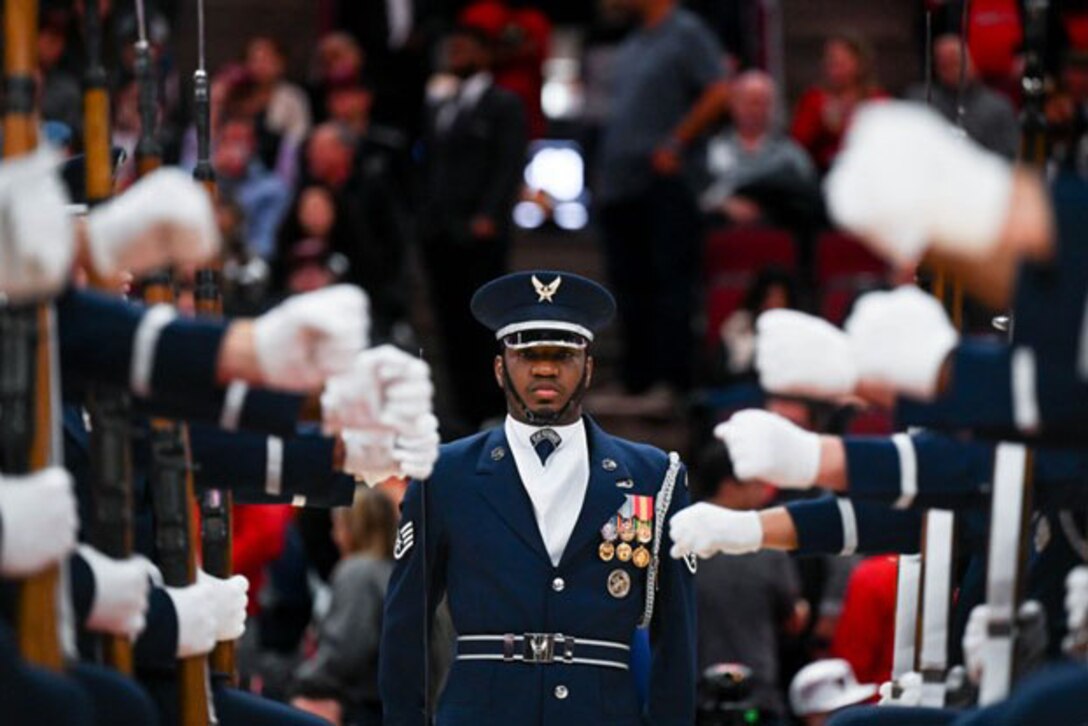 An airman prepares to walk between two rows of airmen wearing formal uniforms.