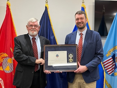 Doug Smith stands with Jim Young holding a plaque