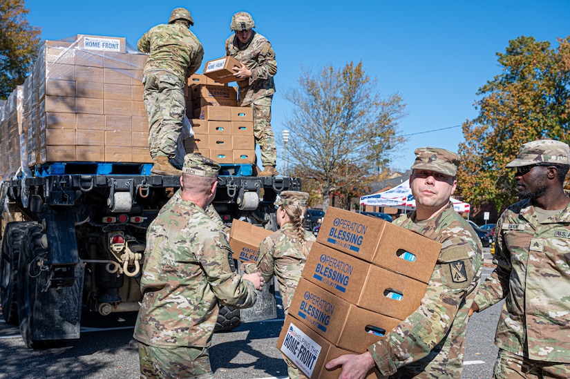 U.S. Army Soldiers from the 11th Transportation Brigade (Expeditionary) and 128th Aviation Brigade, unload food kits from an Oshkosh Heavy Expanded Mobility Tactical Truck during a Thanksgiving turkey give-away at Joint Base Langley-Eustis, Virginia, Nov. 16, 2023.