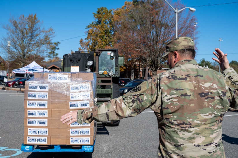 U.S. Army Sgt. 1st Class Kevin Hall, 11th Transportation Brigade (Expeditionary) company 1st sergeant, directs Spc. Deonte Branham 11th TB(X) forklift operator, where to place the pallet of food kits during a Thanksgiving turkey give-away at Joint Base Langley-Eustis, Virginia, Nov. 16, 2023.