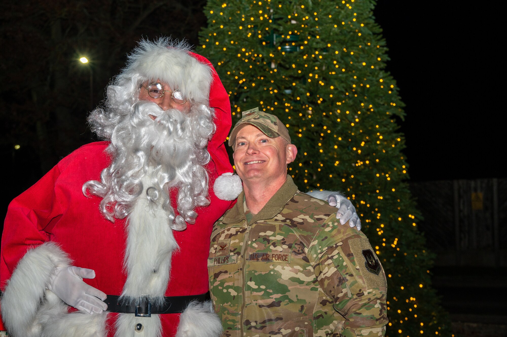 Santa and the base commander pose for a photo in front of a Christmas tree.