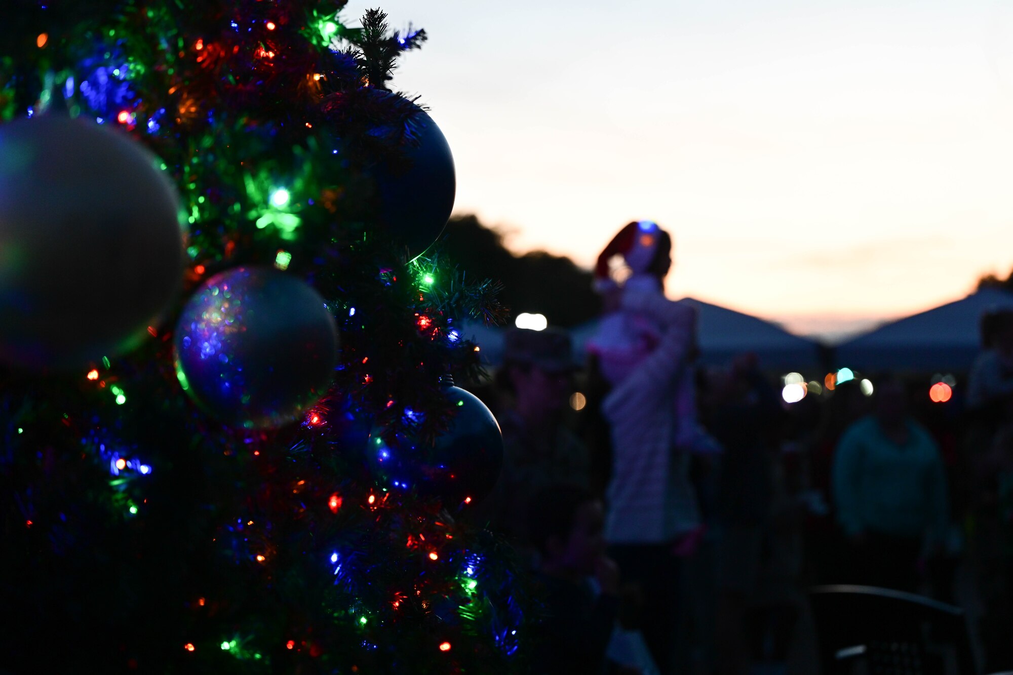 Close-up of lights and ornaments on a Christmas tree and a family in the background