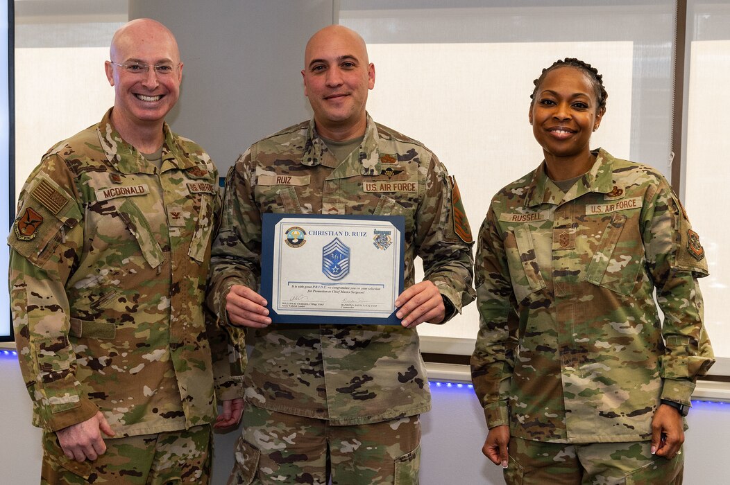 U.S. Air Force Col. Chris McDonald, left, 436th Airlift Wing commander, and U.S. Air Force Chief Master Sgt. Carolyn Russell, right, 436th AW command chief, present U.S. Air Force Senior Master Sgt. Christian Ruiz, 436th Aerial Port Squadron air freight superintendent, with a certificate announcing his selection to chief master sergeant at Dover Air Force Base, Delaware, Nov. 29, 2023. Ruiz was one of 506 Airmen selected for promotion to the top enlisted rank of chief for the 23E9 promotion cycle. (U.S. Air Force photo by Roland Balik)