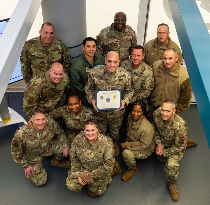 U.S. Air Force Senior Master Sgt. Christian Ruiz, 436th Aerial Port Squadron air freight superintendent, holds his certificate while standing among chief master sergeants, announcing his selection to chief master sergeant at Dover Air Force Base, Delaware, Nov. 29, 2023. Ruiz was one of 506 Airmen selected for promotion to the top enlisted rank of chief for the 23E9 promotion cycle. (U.S. Air Force photo by Roland Balik)