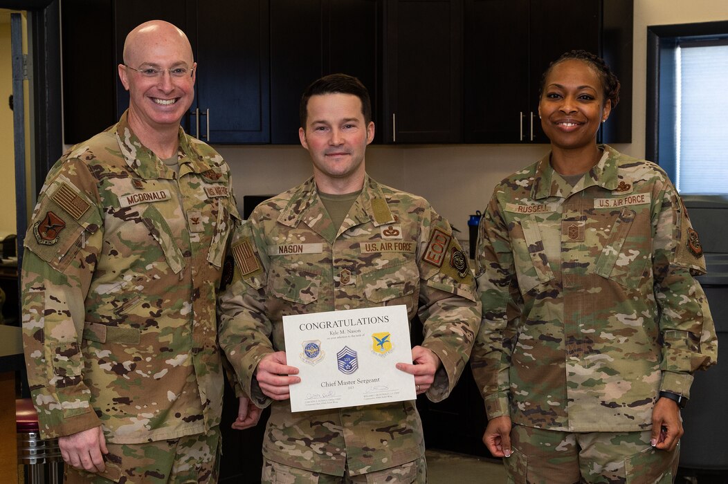 U.S. Air Force Col. Chris McDonald, left, 436th Airlift Wing commander, and U.S. Air Force Chief Master Sgt. Carolyn Russell, right, 436th AW command chief, present U.S. Air Force Senior Master Sgt. Kyle Nason, 436th Civil Engineer Squadron Explosive Ordnance Disposal flight superintendent, with a certificate announcing his selection to chief master sergeant at Dover Air Force Base, Delaware, Nov. 29, 2023. Nason was one of 506 Airmen selected for promotion to the top enlisted rank of chief for the 23E9 promotion cycle. (U.S. Air Force photo by Roland Balik)