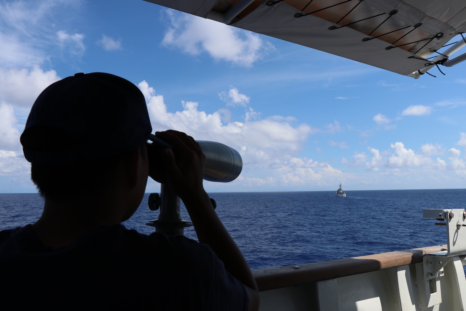 U.S. Coast Guard Seaman Lin Han, a crewmember assigned to Coast Guard Cutter Bear (WMEC 901), stands a lookout-watch with U.S. Coast Guard Cutter Vigilant (WMEC 617) in his sights, in the Caribbean Sea, Oct. 22, 2023. Bear and Vigilant supported Joint Interagency Task Force South within the Coast Guard's Seventh District. (U.S. Coast Guard photo by Ensign Melody Silva)