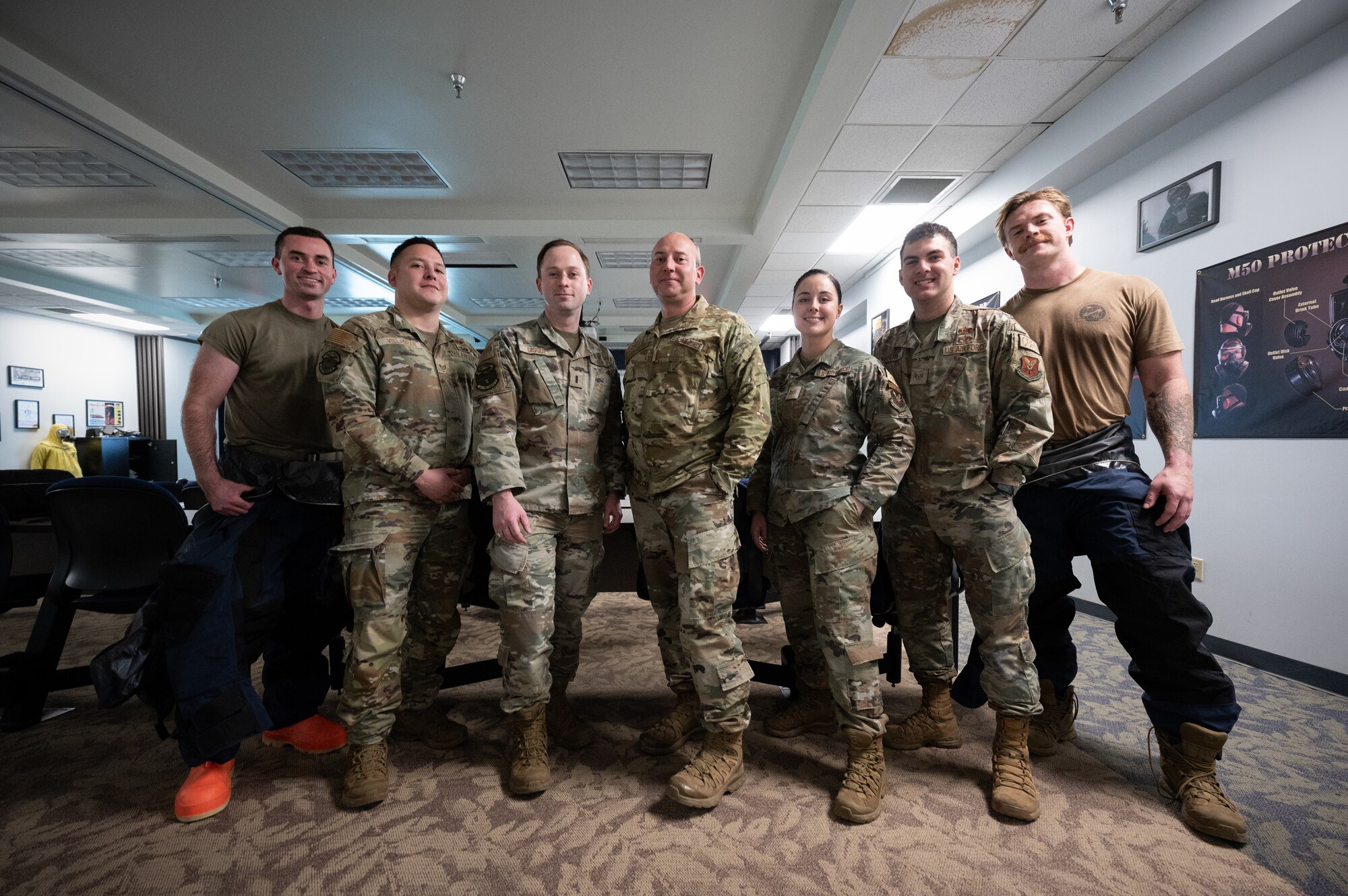 A group of seven uniformed military personnel stand next to each other in a line for a group photo.