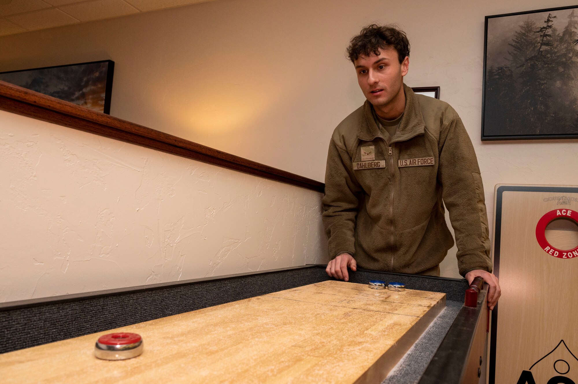 U.S. Air Force Airman 1st Class Nicholas Dahlberg, 49th Equipment Maintenance Squadron aircrew ground equipment journeyman, plays a game of shuffleboard in the 49th Maintenance Group new resiliency and relaxation room at Holloman Air Force Base, New Mexico, Nov. 29, 2023.