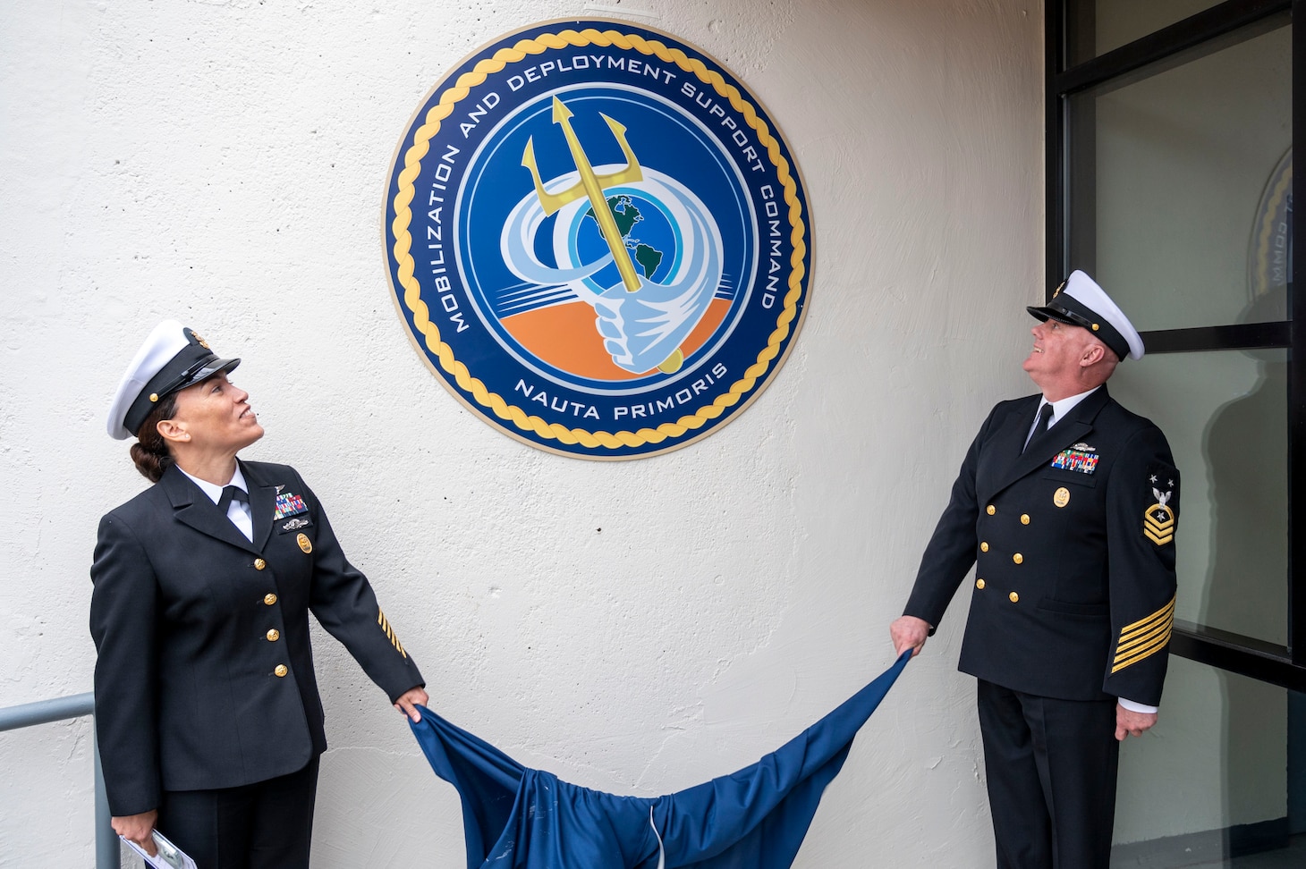 Command Master Chief Nicole Rios and Command Master Chief Michael Harvie unveil the seal for Mobilization and Deployment Support Command during the launch ceremony for Mobilization and Deployment Support Command.