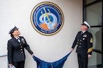 Command Master Chief Nicole Rios and Command Master Chief Michael Harvie unveil the seal for Mobilization and Deployment Support Command during the launch ceremony for Mobilization and Deployment Support Command.