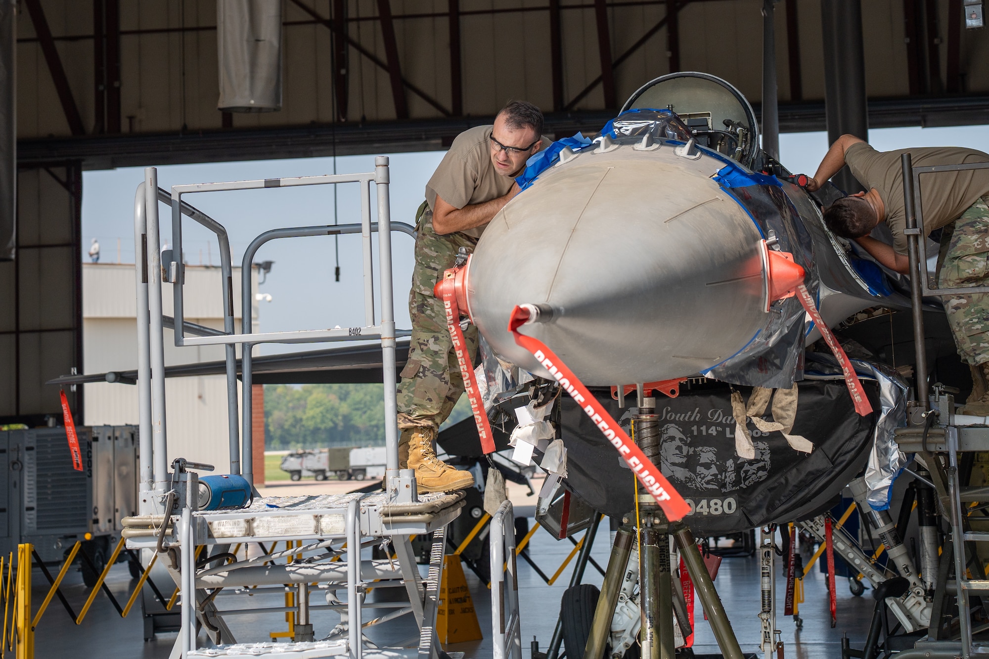 Staff Sgt. Zach Hallstrom and Staff Sgt. Bryce Engbarth, 114th Maintenance Squadron aircraft structural airman, works on removing parts on a F-16 during the canopy sill longeron repair.