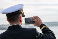 Lt. j. g. David Moya, a chaplain assigned to the Arleigh Burke-class guided-missile destroyer USS Paul Ignatius (DDG 117) takes a photo from the pier at Naval Station (NAVSTA) Rota as the ship returns from deployment, Nov. 28, 2023. As the "Gateway to the Mediterranean,” NAVSTA Rota provides U.S, NATO and allied forces a strategic hub for operations in Europe, Africa and the Middle East. NAVSTA Rota is a force multiplier, capable of promptly deploying and supporting combat-ready forces through land, air and sea, enabling warfighters and their families, sustaining the fleet and fostering the U.S. and Spanish partnership. (U.S. Navy photo by Mass Communication Specialist 2nd Class Drace Wilson)