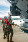 Air Traffic Controller 1st Class David Sudbeck, assigned to Naval Support Activity (NSA) Souda Bay, heaves line to bring in the first-in-class aircraft carrier USS Gerald R. Ford (CVN 78) as the ship arrives in Souda Bay, Crete, for a scheduled port visit on Dec. 2, 2023. USS Gerald R. Ford Carrier Strike Group is on a scheduled deployment in the U.S. Naval Forces Europe-Africa area of operations, employed by U.S. Sixth Fleet to defend U.S., allied and partner interests. NSA Souda Bay is an operational ashore installation which enables and supports U.S., Allied, Coalition, and Partner nation forces to preserve security and stability in the European, African, and Central Command areas of responsibility. (U.S. Navy photo by Mass Communication Specialist 1st Class Delaney S. Jensen)
