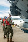 Air Traffic Controller 1st Class David Sudbeck, assigned to Naval Support Activity (NSA) Souda Bay, heaves line to bring in the first-in-class aircraft carrier USS Gerald R. Ford (CVN 78) as the ship arrives in Souda Bay, Crete, for a scheduled port visit on Dec. 2, 2023. USS Gerald R. Ford Carrier Strike Group is on a scheduled deployment in the U.S. Naval Forces Europe-Africa area of operations, employed by U.S. Sixth Fleet to defend U.S., allied and partner interests. NSA Souda Bay is an operational ashore installation which enables and supports U.S., Allied, Coalition, and Partner nation forces to preserve security and stability in the European, African, and Central Command areas of responsibility. (U.S. Navy photo by Mass Communication Specialist 1st Class Delaney S. Jensen)