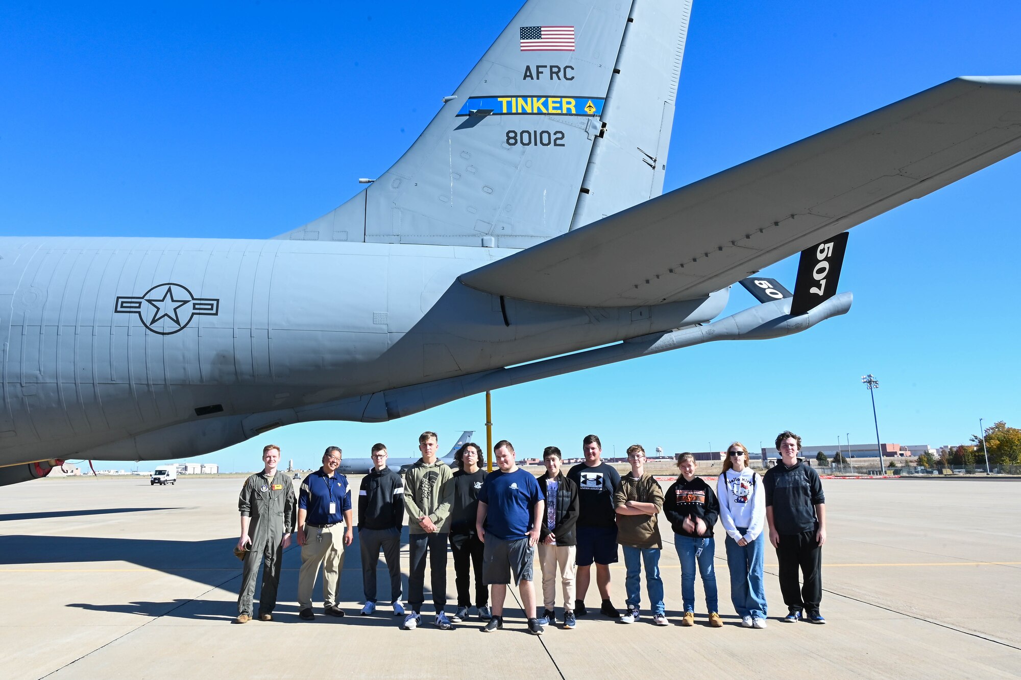 people taking a group picture under a plane tail