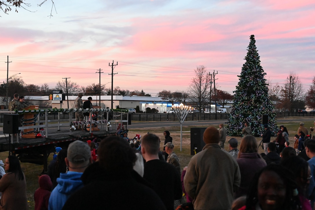 A crowd watches as a Christmas tree and menorah are lit during a ceremony.