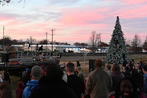 A crowd watches as a Christmas tree and menorah are lit during a ceremony.