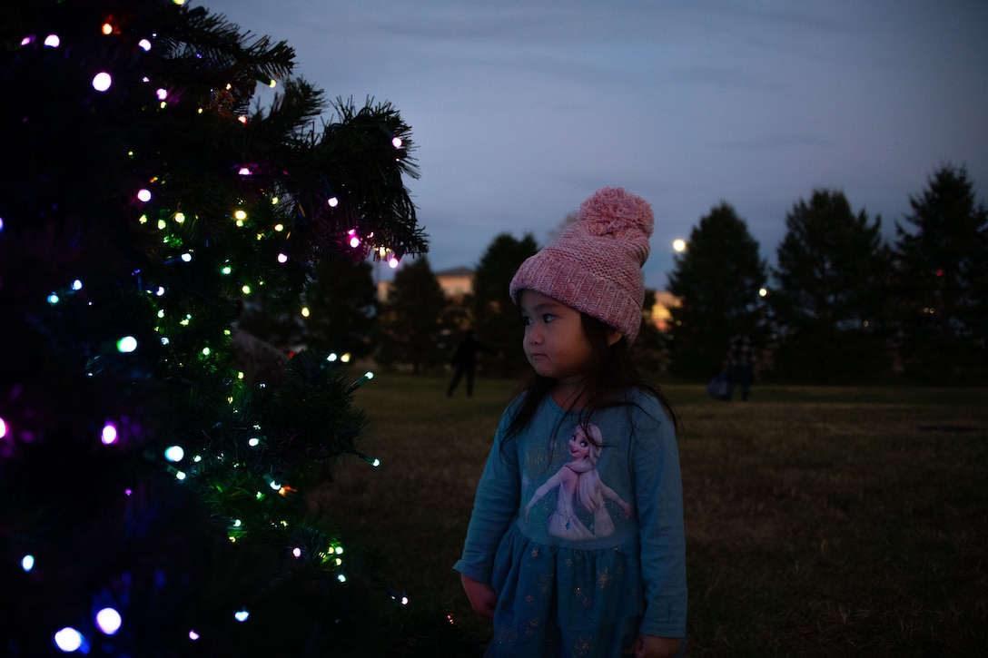 A girl admires the lights on a Christmas tree