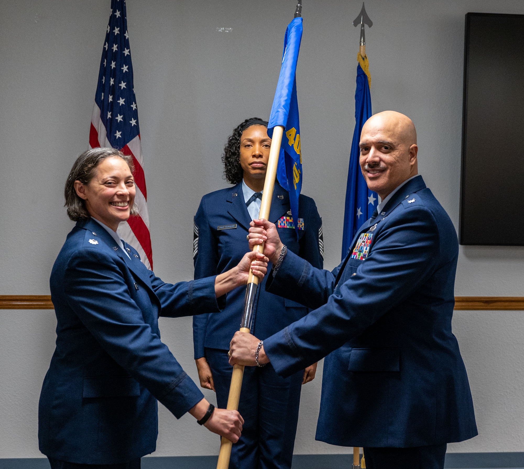 Breal hands a flag to Roldan. Chief Latoya Patterson stands in teh middle.