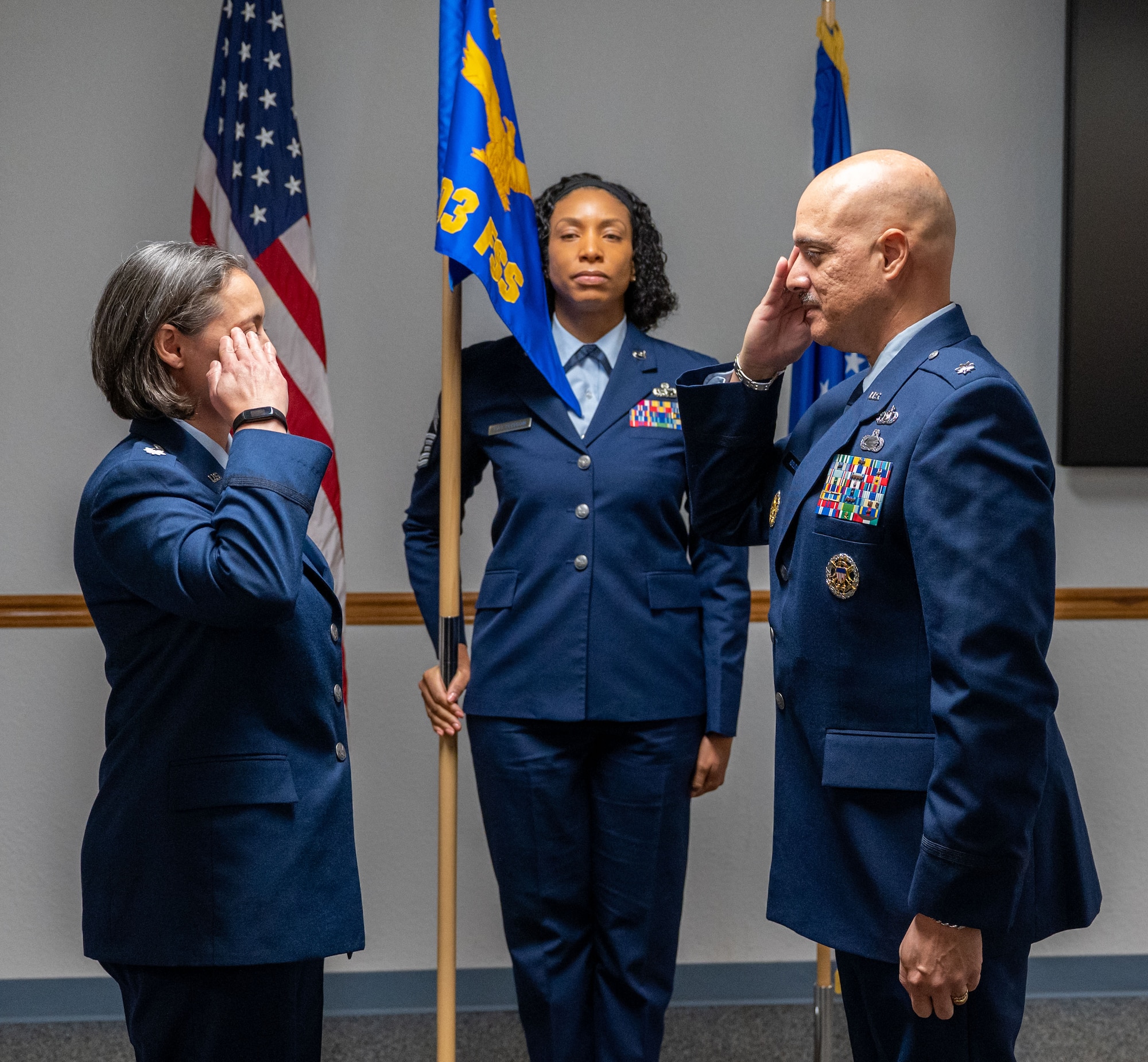 Breal and Roldan salute. Chief Latoya Patterson stands in between them holding a unit flag.