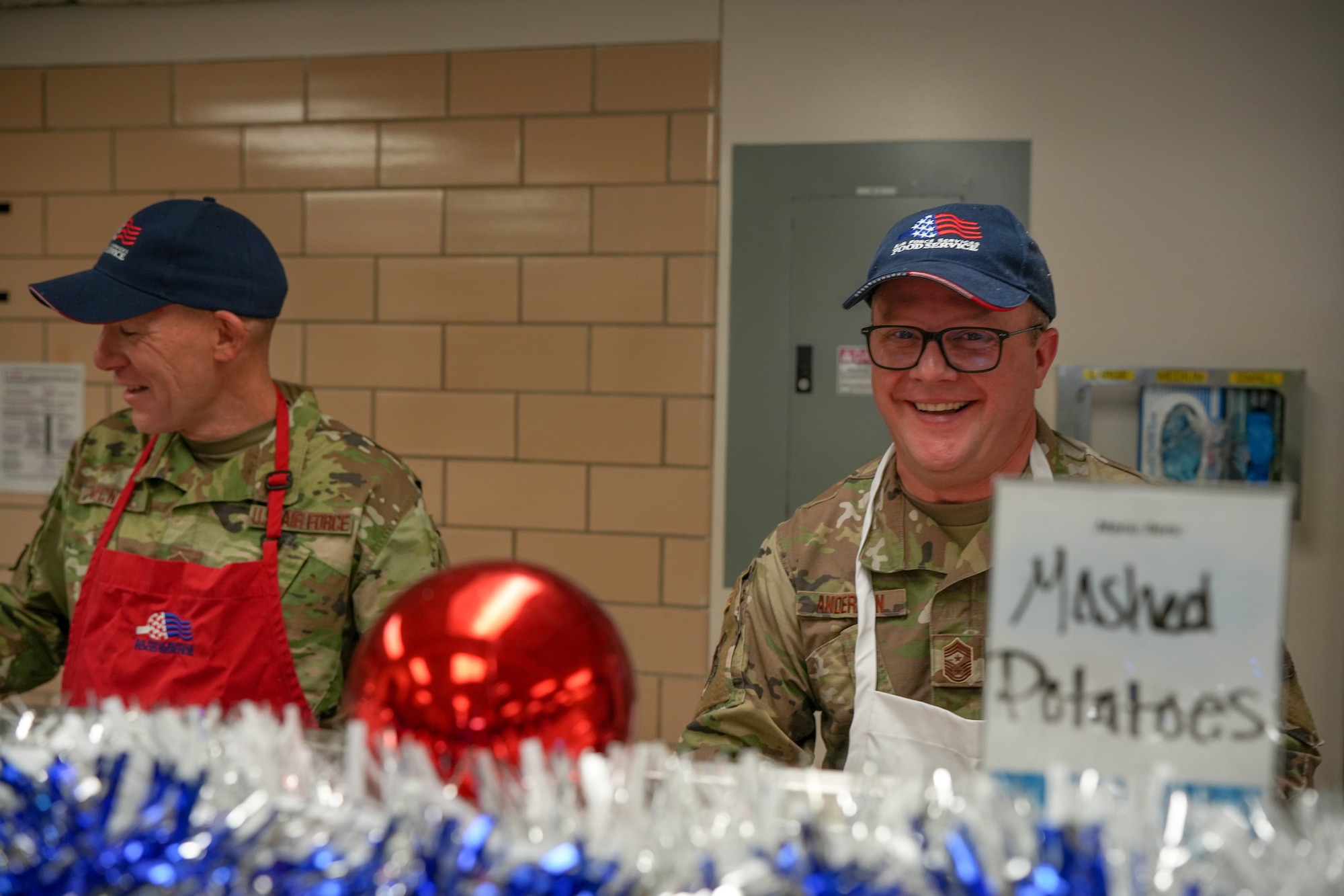 U.S. Air National Guard Chief Master Sgt. Daniel McNeil, left, 114th operations superintendent and Command Chief Master Sgt. Andy Anderson, right, South Dakota National Guard state command chief, serve a holiday meal to Airmen during December's unit training assembly at Joe Foss Field, South Dakota, December 2, 2023.