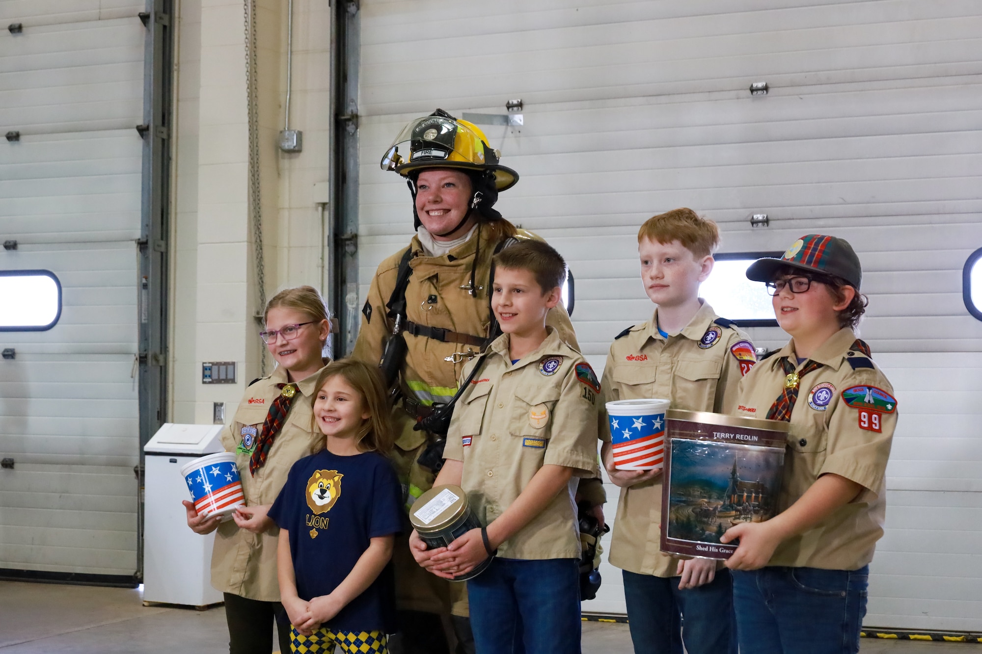 Boy Scouts of America Sioux Council Pack 208 pose with Airman 1st Class Georgia Kuehn, fire protection, after bringing popcorn to members of the South Dakota Air National Guard during December's unit training assembly, marking the launch of a partnership between the two organizations, December 2, 2023.