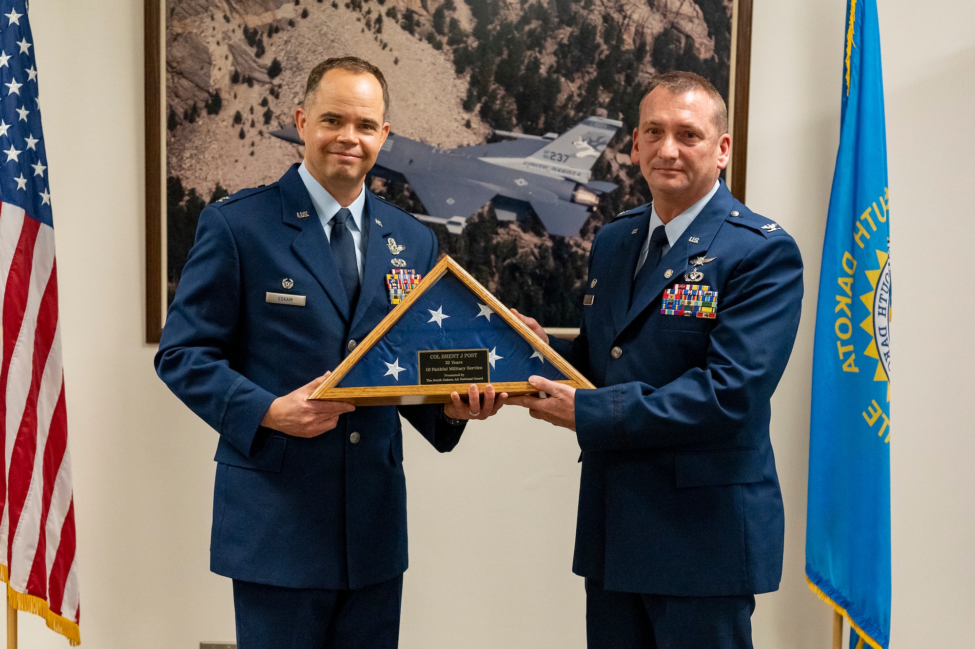 U.S. Air Force Col. Brandon Eskam, left, 114th Fighter Wing commander, presents U.S. Air Force Col. Brent Post, retired, with an honorary service flag at Post’s retirement ceremony at Joe Foss Field, S.D., Dec. 3, 2023.