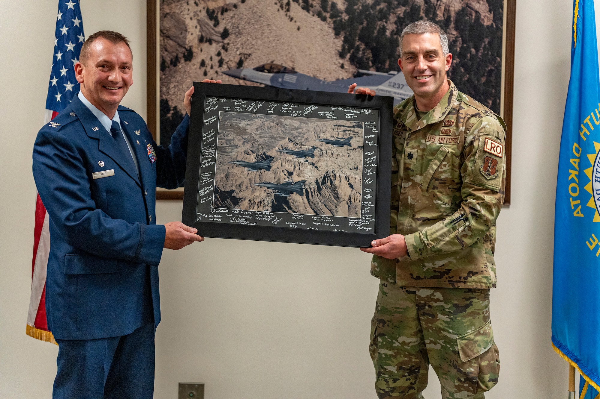 U.S. Air Force Lt. Col. Matthew Kayser, right, 114th Logistics Readiness commander, presents U.S. Air Force Col. Brent Post, retired, with a signed photo at Post’s retirement ceremony at Joe Foss Field, S.D., Dec. 3, 2023.