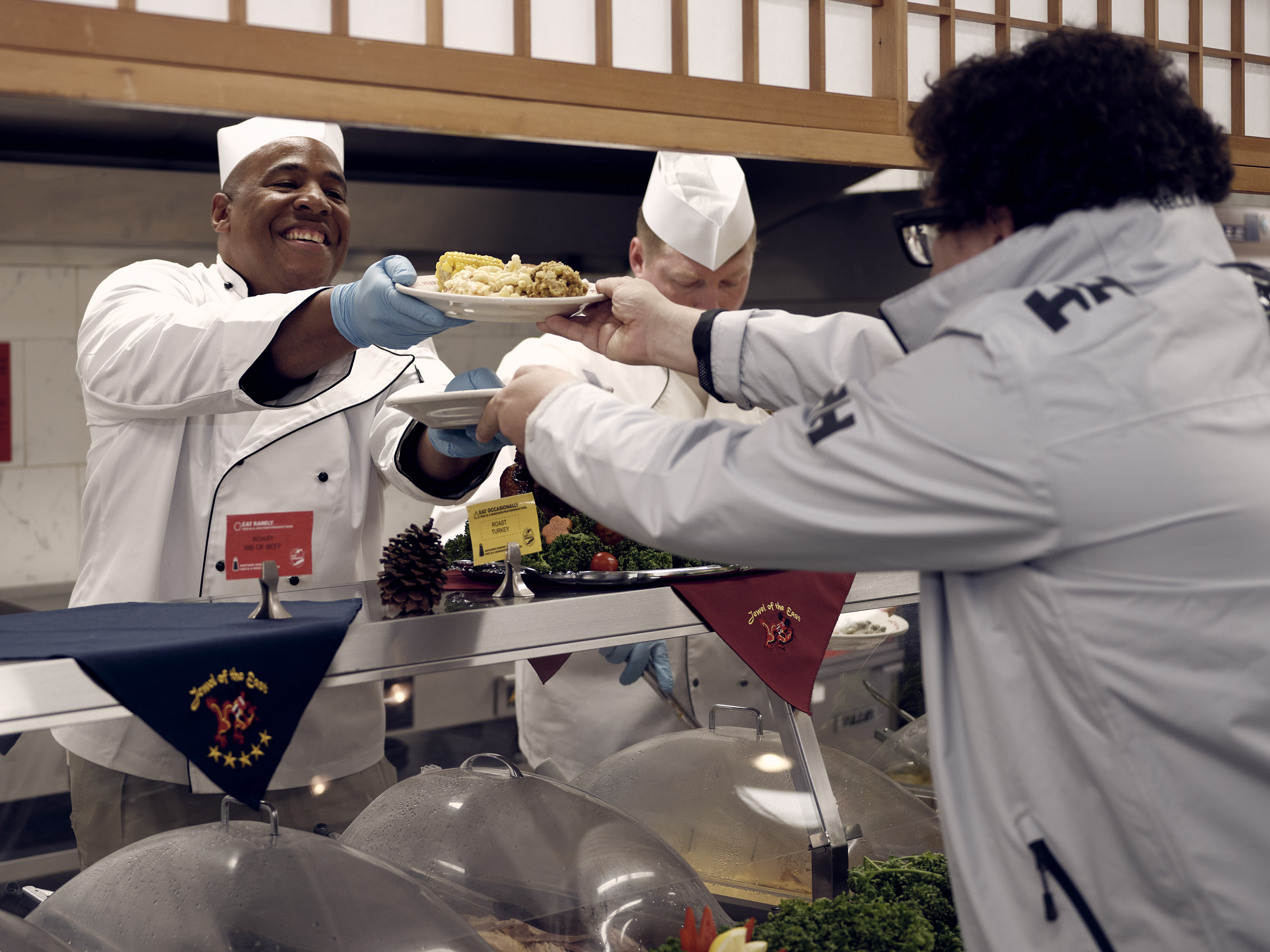 A sailor serves Thanksgiving dinner to a military base family member.