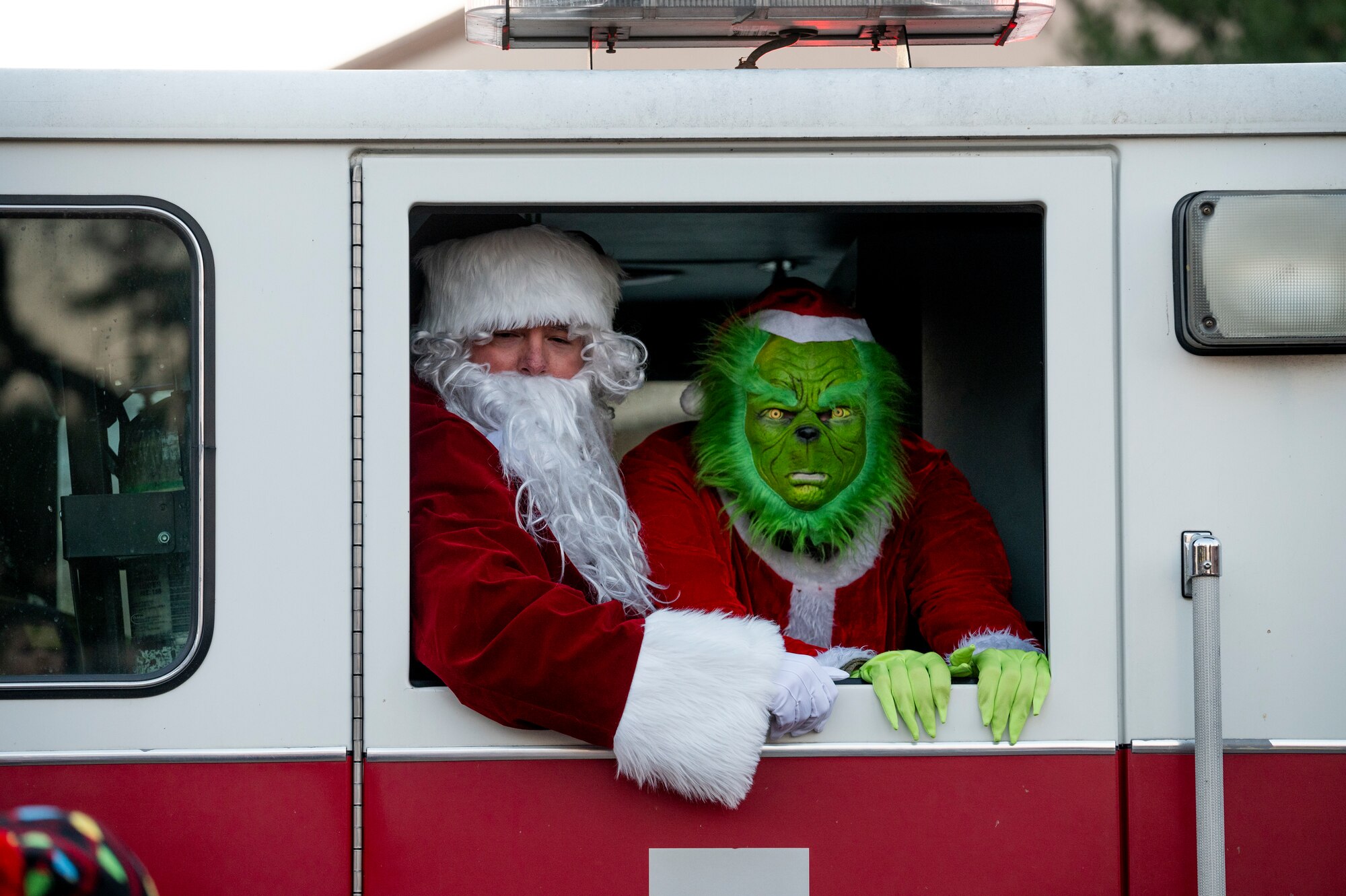 Santa Claus and the Grinch drive by in a 51st Civil Engineer Squadron fire truck during the Christmas Tree Lighting Ceremony at Osan Air Base, Republic of Korea, Dec. 1, 2023.