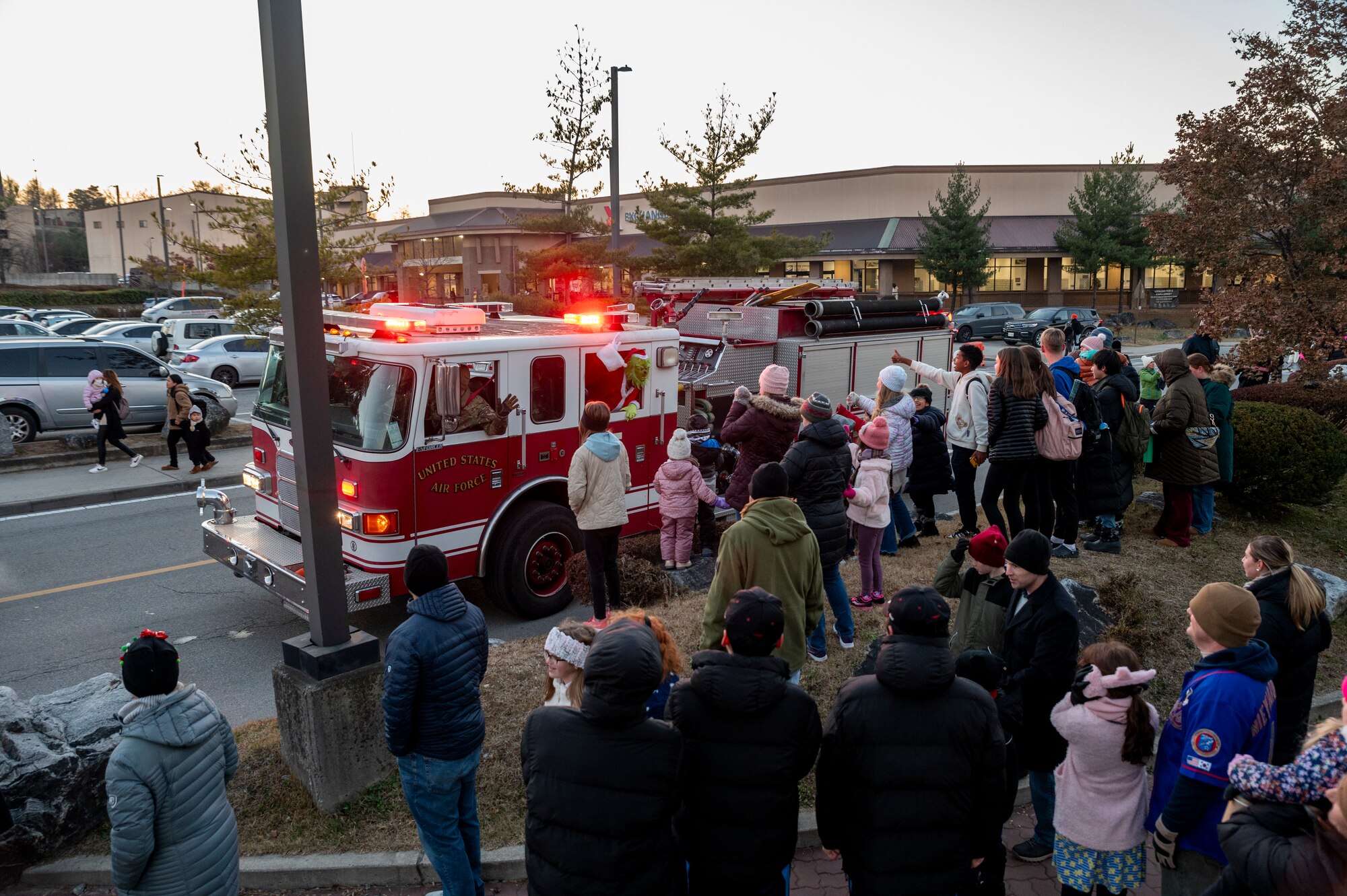 U.S. Airmen and family members from the Osan community wave at Santa Claus as he rides by in a 51st Civil Engineer Squadron fire truck during the Christmas Tree Lighting Ceremony outside the base theater at Osan Air Base, Republic of Korea, Dec. 1, 2023.