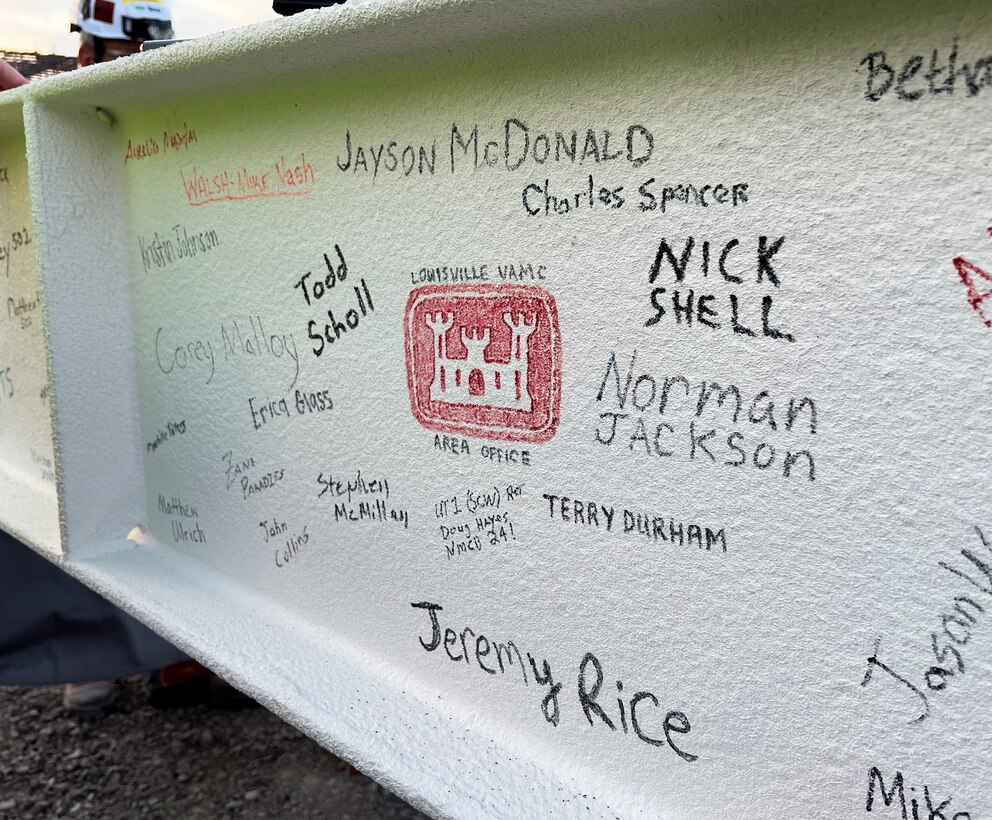 Signatures of workers on the project have been written on a steel beam that has been painted white.
