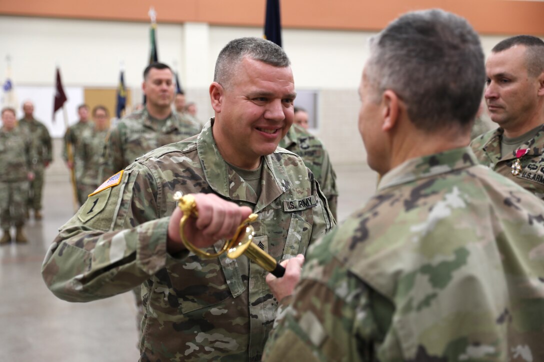 Col. Jade Beehler, commander of the 64th Troop Command, hands off the noncommissioned officer’s sword to Command Sgt. Maj John Buck, the incoming 64th Troop Command senior enlisted leader, during a change of responsibility ceremony Dec. 2 at the US Armed Forces Reserve Center in Madison, Wis. The change of responsibility ceremony celebrates the outgoing command sergeant major and welcomes the incoming command sergeant major. 112th Mobile Public Affairs Detachment photo by Spc. Emiliano Alcorta