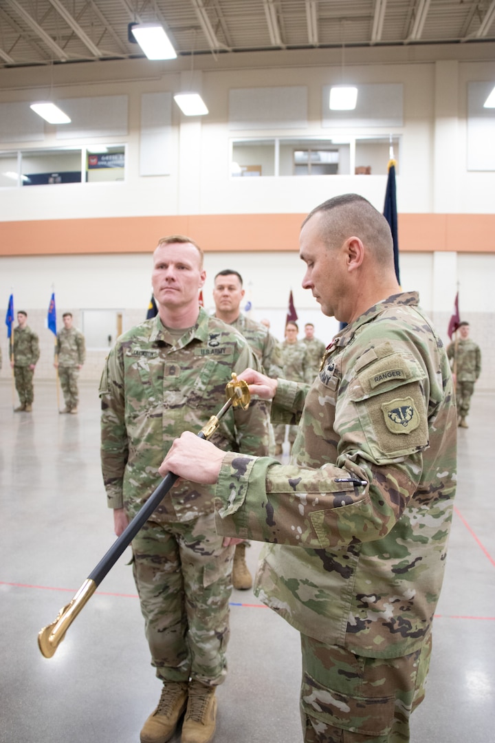 Master Sgt. Daniel Jackson (left) hands off the noncommissioned officer sword to outgoing 64th Troop Command Brigade Command Sgt. Maj. Gregory Fulton, signifying a relinquishment of his position during a change of responsibility ceremony Dec. 2 at the Joint Force Reserve Center in Madison, Wis. After serving in that position for almost two years and serving in the Army for 32 years, Fulton is retiring. (U.S. Army National Guard photo by Spc. Abaigail Intine)
