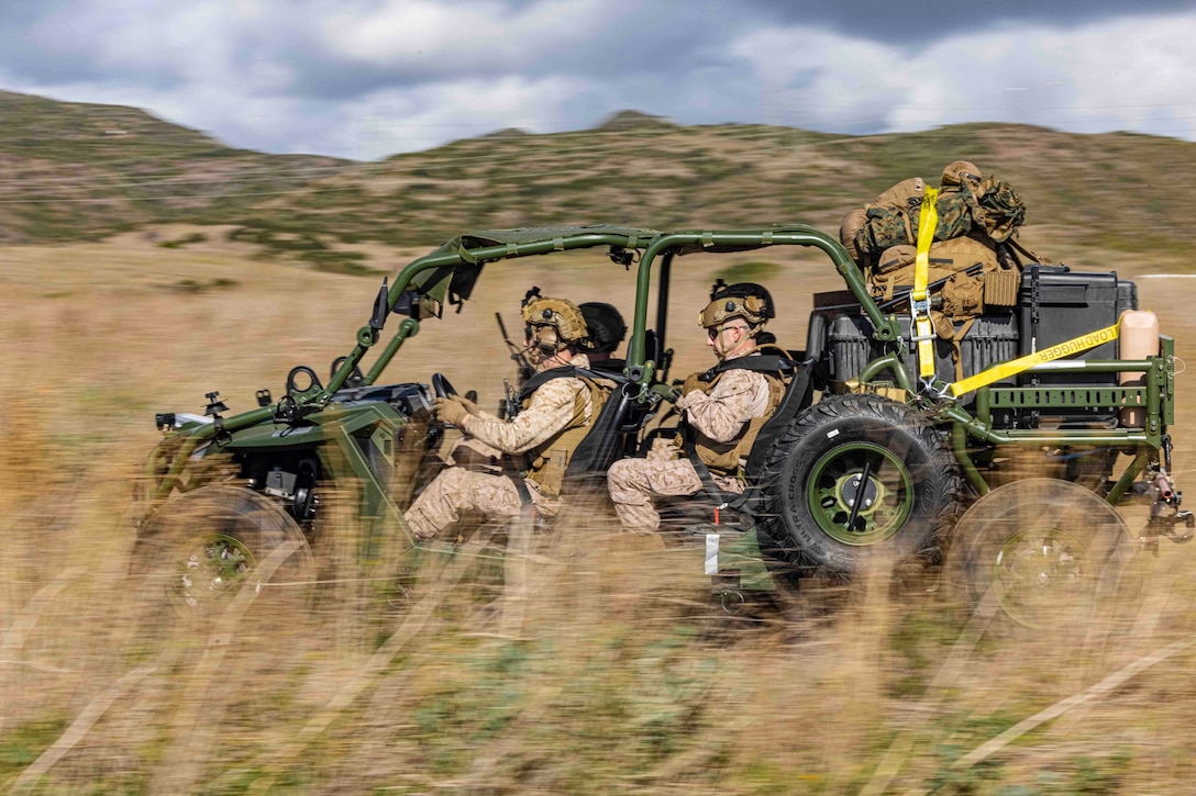 Marines ride in a military vehicle through desert terrain.