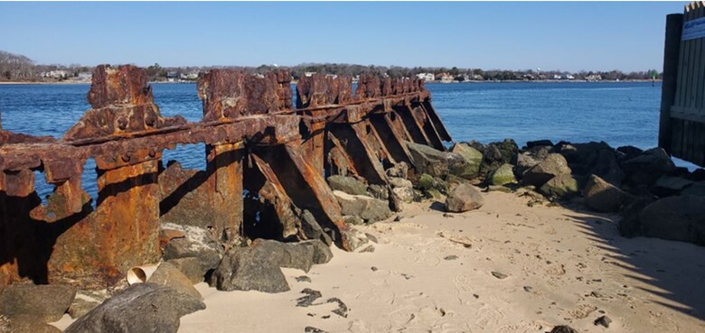 Photo shows a deteriorated steel bulkhead/wall structure in front of a waterway