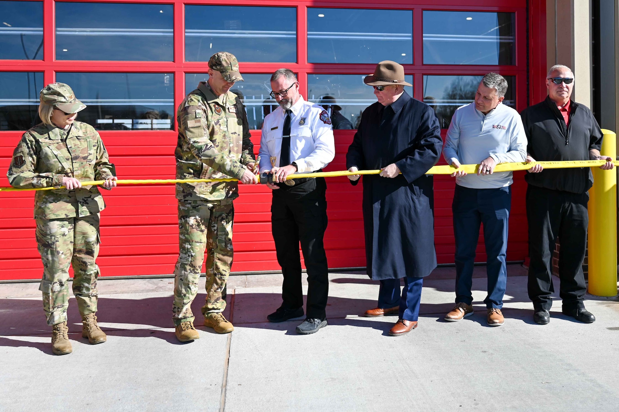 U.S. Air Force Col. Jeff Marshall (left), 97th AMW commander, and Chief Phillip Fourroux (right), 97th Civil Engineer Squadron fire chief, untwist a hose to commemorate the opening of the headquarters fire station at Altus Air Force Base (AFB), Oklahoma, Dec. 1, 2023. Following the commemoration, attendees had the opportunity to tour the station to see what the new facility looks like. (U.S. Air Force photo by Airman 1st Class Kari Degraffenreed)