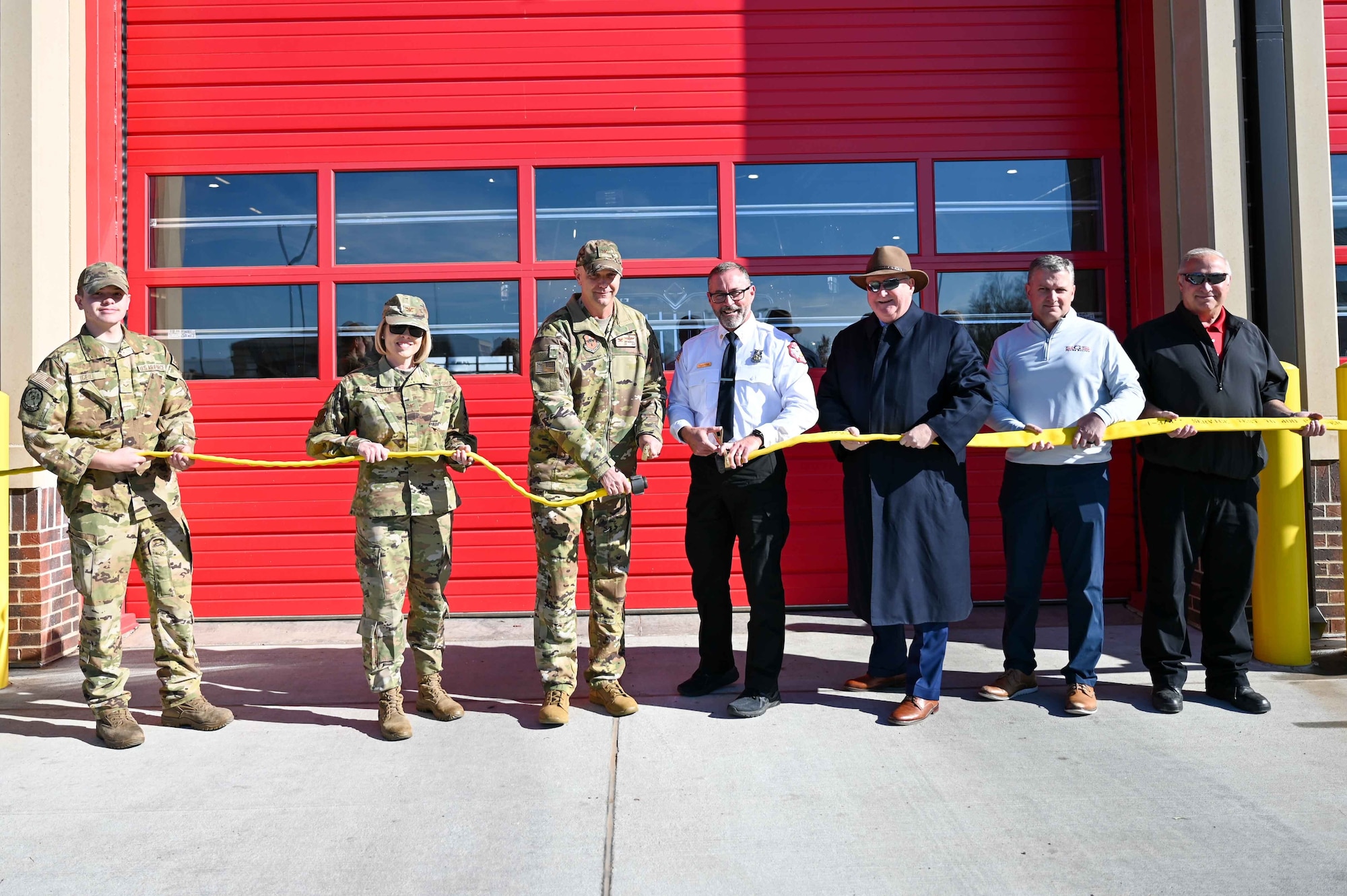 97th Air Mobility Wing (AMW) leadership and members of the Military Affairs Committee untwist a hose to commemorate the opening of the headquarters fire station at Altus Air Force Base, Oklahoma, Dec. 1, 2023. The new station will provide aircraft crash rescue and firefighting services, as well as firefighting equipment, a fire alarm system, and an emergency communications sensor center. (U.S. Air Force photo by Airman 1st Class Kari Degraffenreed)