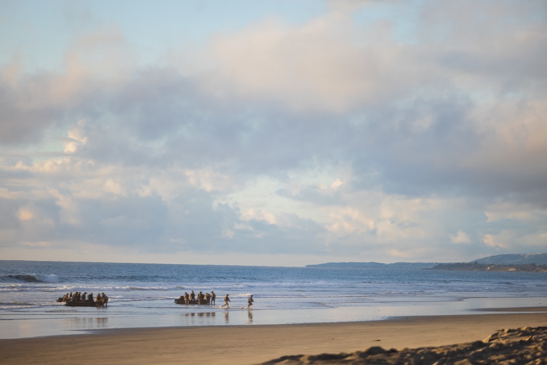 U.S. Marines with Charlie Company, 1st Reconnaissance Battalion, 1st Marine Division, carry rigid-hull inflatable boats ashore at Red Beach during a raid as part of Exercise Steel Knight 23.2 at Marine Corps Base Camp Pendleton, California, Nov. 30, 2023. Steel Knight is a three-phase exercise designed to train I Marine Expeditionary Force in the planning, deployment and command and control of a joint force against a peer or near-peer adversary combat force and enhance existing live-fire and maneuver capabilities of the Marine Air-Ground Task Force. (U.S. Marine Corps photo by Cpl. Daniel)