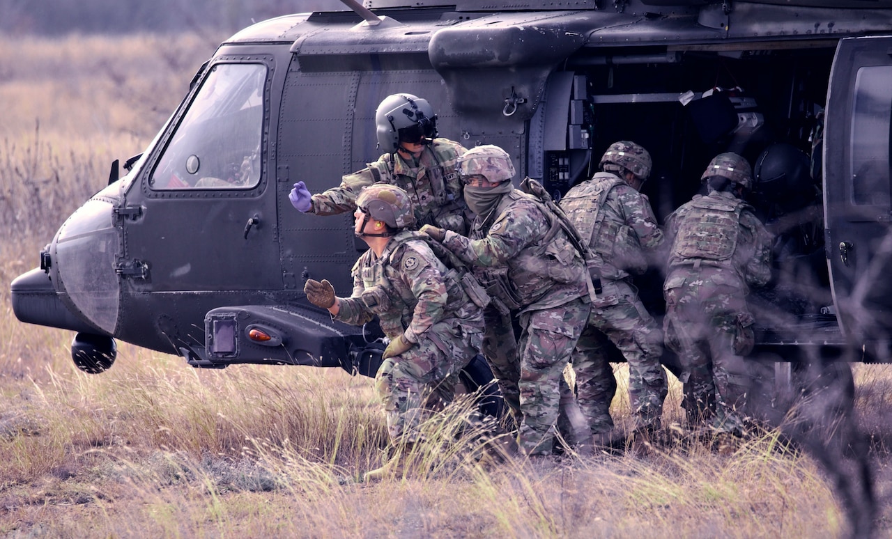 Soldiers train next to a helicopter.
