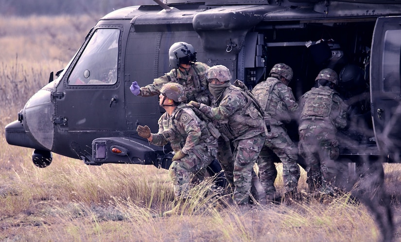 يتدرب الجنود بجوار طائرة هليكوبتر.