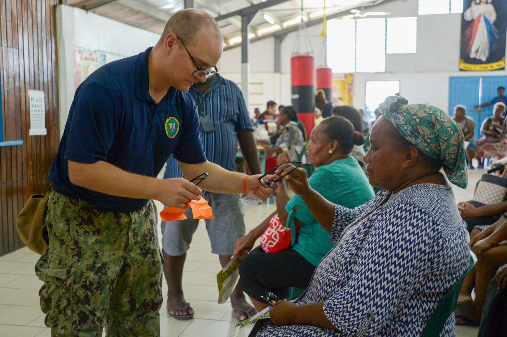 U.S. Navy Hospital Corpsman 2nd Class Dzmitry Astapchyk, from Toms River, New Jersey, gives a local resident glasses during a community health engagement at the Holy Cross Cathedral in Honiara, Solomon Islands, as part of Pacific Partnership 2024-1, Dec. 2, 2023. Pacific Partnership, now in its 19th iteration, is the largest multinational humanitarian assistance and disaster relief preparedness mission conducted in the Indo-Pacific and works to enhance regional interoperability and disaster response capabilities, increase security stability in the region, and foster new and enduring friendships. (U.S. Navy photo by Mass Communication Specialist 2nd Class Jacob Woitzel)