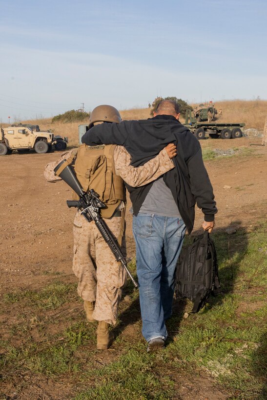 U.S. Marine Corps Pfc. Edgar Pizana, left, a motor transport operator with Combat Logistics Battalion 5, Combat Logistics Regiment 1, 1st Marine Logistics Group, assists a role-player at an evacuation control center during a mission rehearsal exercise as part of Exercise Steel Knight 23.2 at Marine Corps Base Camp Pendleton, California, Dec. 1, 2023. Steel Knight maintains and sharpens I Marine Expeditionary Force as America’s expeditionary force in readiness – organized, trained and equipped to respond to any crisis, anytime, anywhere. This exercise will certify the battalion and 5th Marine Regiment, 1st Marine Division, to be forward-postured in Australia as Marine Rotational Force - Darwin, a six-month deployment during which Marines train with Australian allies and facilitate rapid response to crises and contingencies. Pizana is a native of Dallas. (U.S. Marine Corps photo by Sgt. Cristian Bestul)